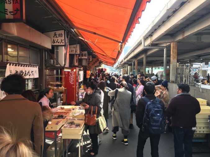 A crowded alleyway with food stands on the side